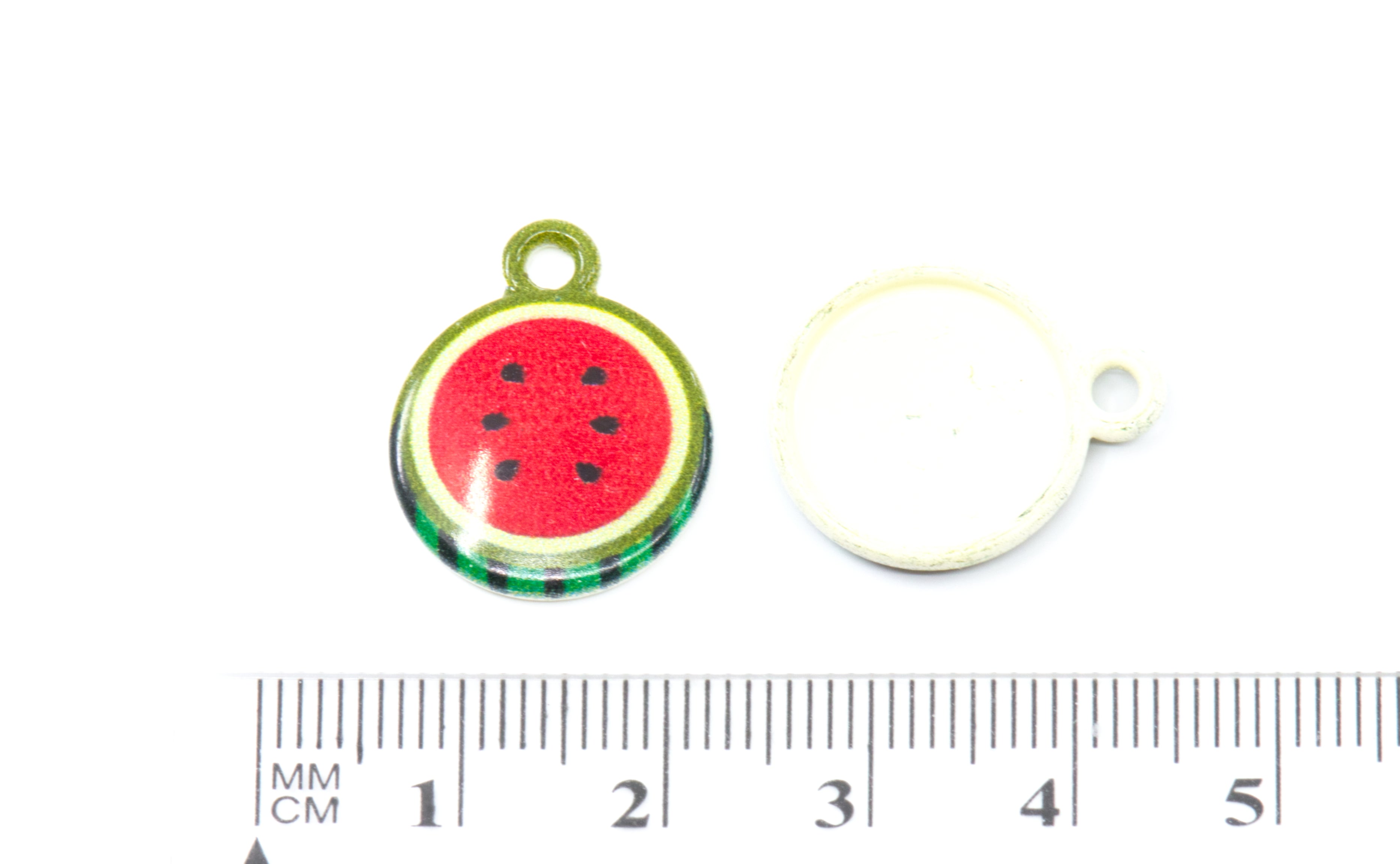 two small round watermelon-themed charm with a green top loop and a white back piece, shown next to a centimeter ruler for scale on a white background.