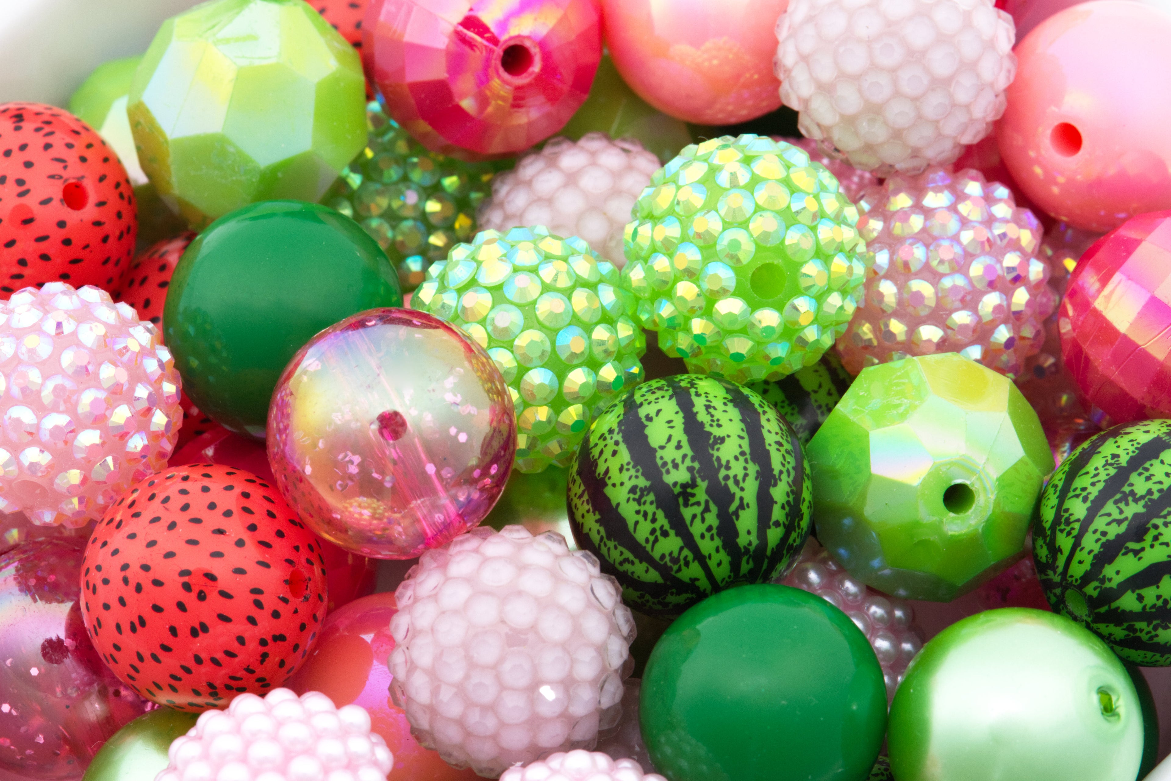 A close-up pile of colorful bubblegum beads with various patterns and textures, including watermelon print, faceted, iridescent rhinestones, and smooth glossy finishes.
