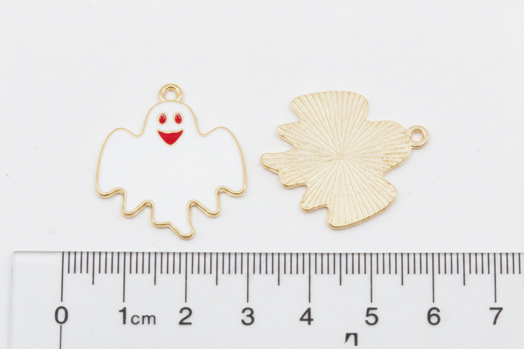 Two white ghost charms on a gray background with a ruler at the bottom for scale. 